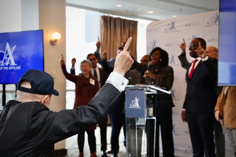 Cherelle Parker leading a room of people during a press conference holding up one finger for her 'One Philly' chant