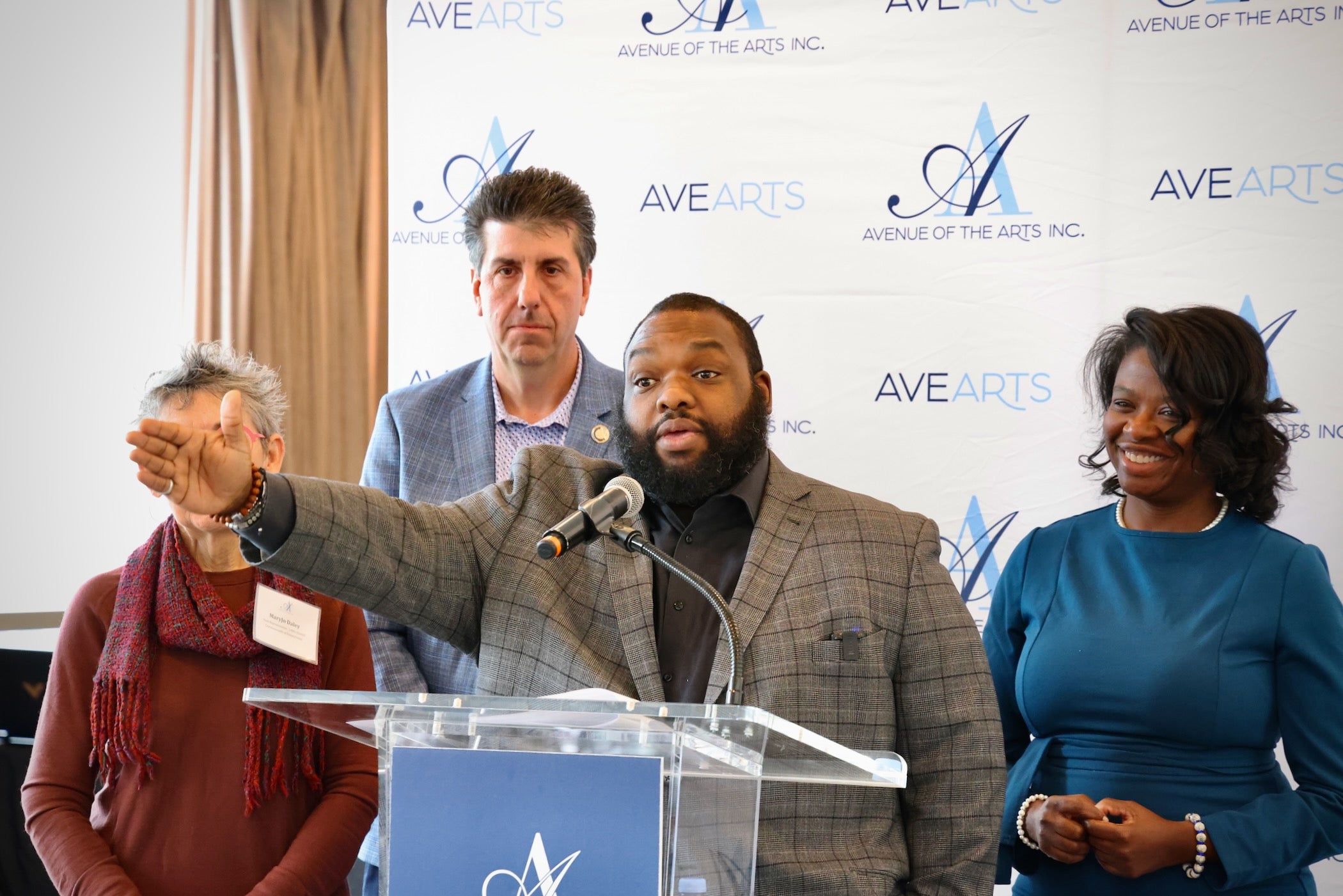 Jordan Harris extends one arm as he speaks at a podium with other officials standing behind him.
