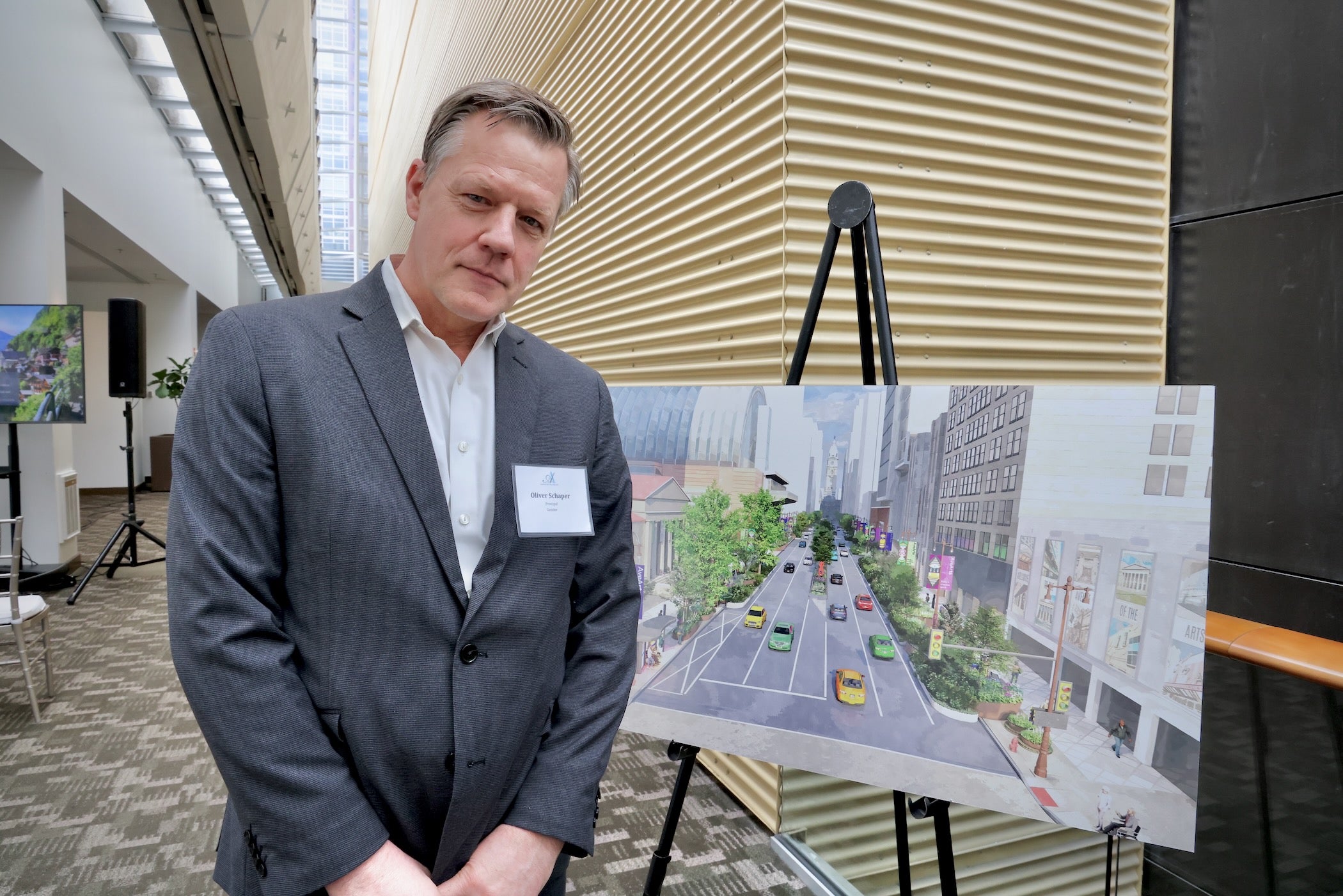 Oliver Schaper posing for a photo in front of a large rendering of South Broad Street which sits on an easel.