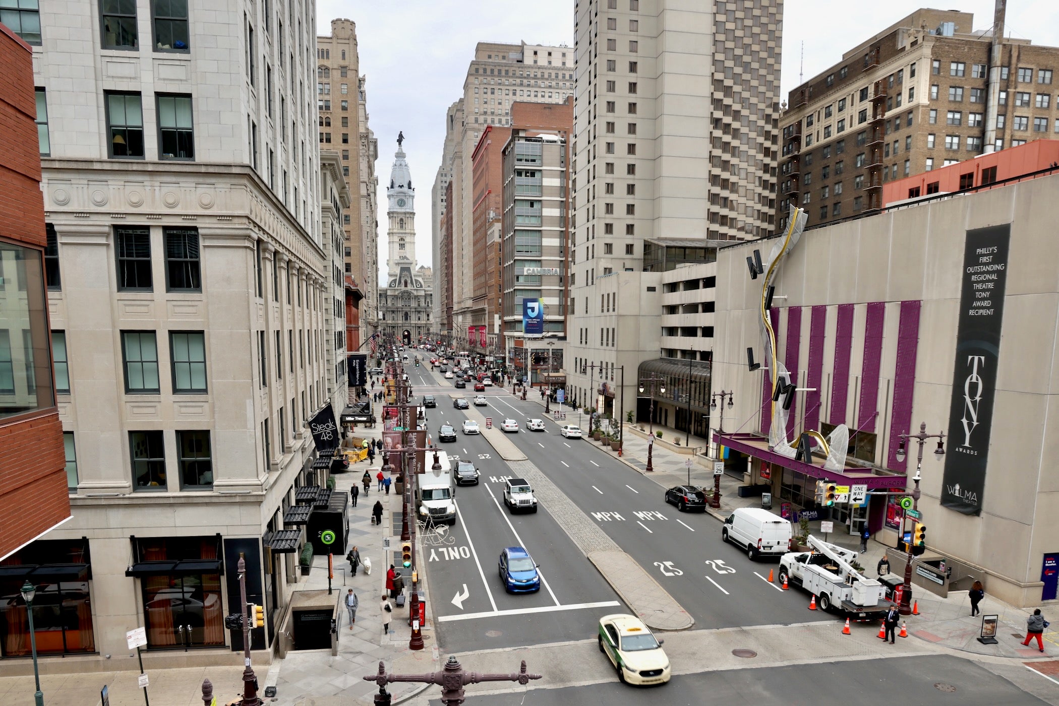 A look at South Broad Street facing City Hall during a busy afternoon with many people and cars.