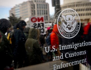 2026 01 19-e lee-philadelphia 8th and cherry-ice protest reflection Protesters are seen through the glass of an ICE office in Philadelphia