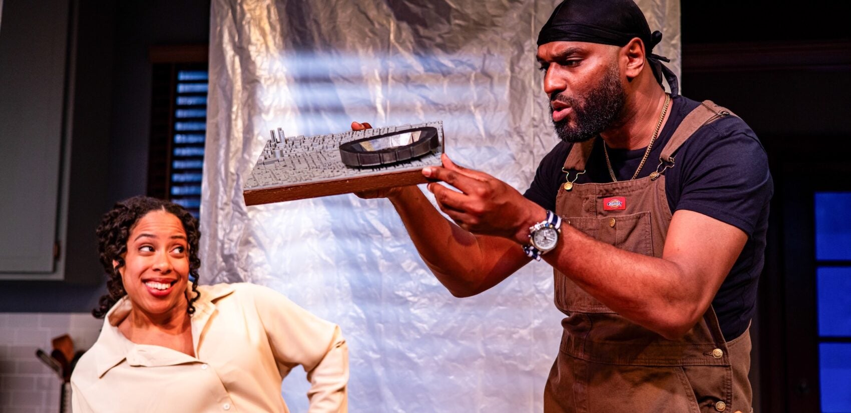 Taysha Marie Canales looks on as Walter DeShields skeptically examines a 3D model of a stadium.