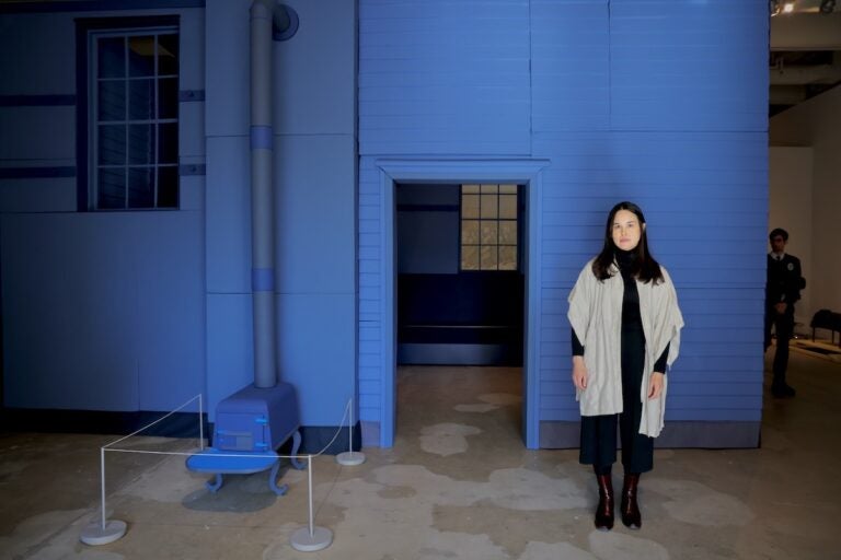 Amie Cunat poses for photo standing beside artwork