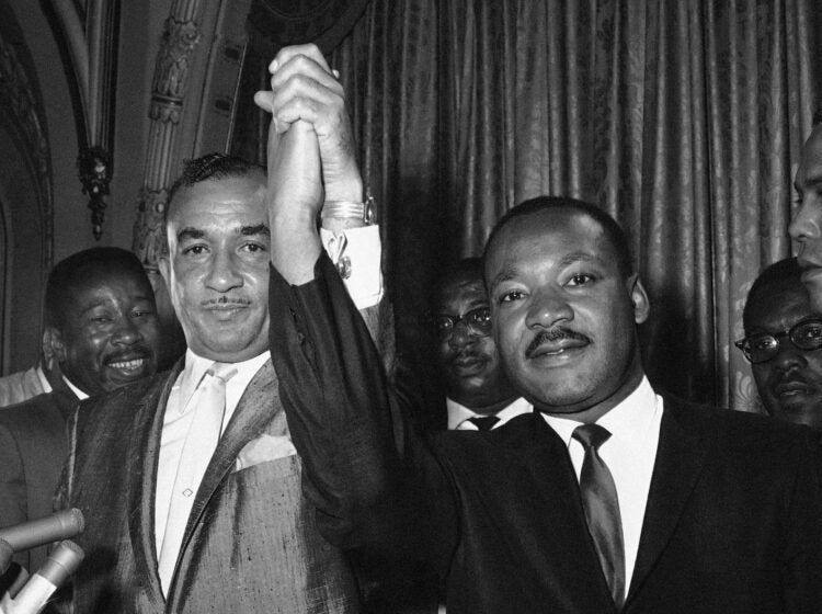 Cecil Moore, left, NAACP, leader in Philadelphia, and Dr. Martin Luther King, integration leader, raises their hands in a gesture of unity in Philadelphia August 2, 1965, where Dr. King started a two-day visit. Moore earlier had requested Dr. King not to come here but they said the controversy was “a misunderstanding.” Dr. King hailed picketing at the all-white Girard College by the NAACP served to “dramatize the problem.” African American  are attempting to break provisions of the college’s founder calling for only white students admitted. (AP Photo/Bill Ingraham )