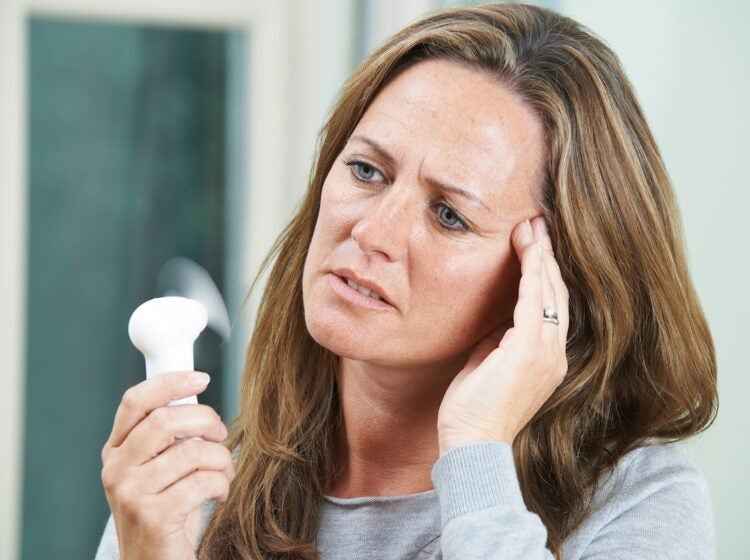 woman experiencing a hot flash, a common menopause symptom (Machineheadz/Bigstock).