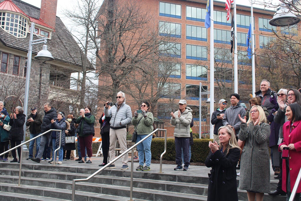 A small crowd of spectators in Bucks County applauds while standing on outside steps