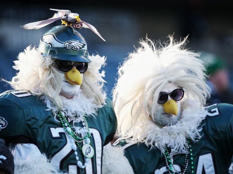 Two Eagles fans at the football stadium dressed in Eagle costumes from head to toe, and wearing jerseys