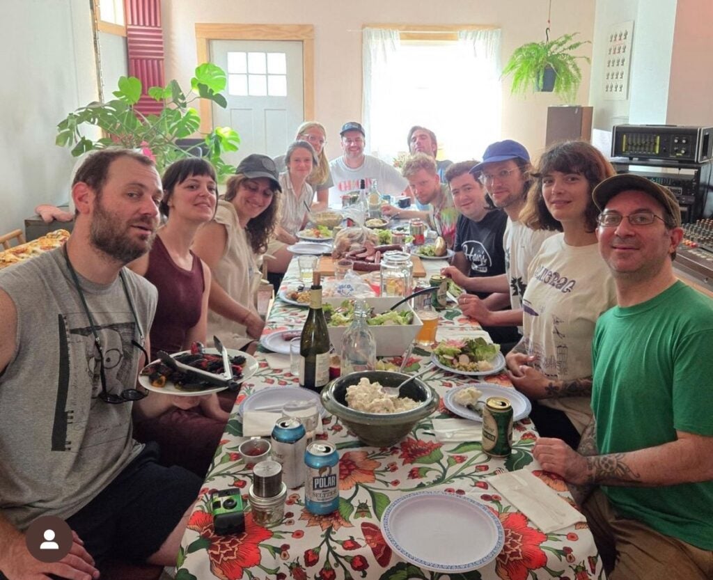 A large group of people sitting inside at a large table with a lot of food.