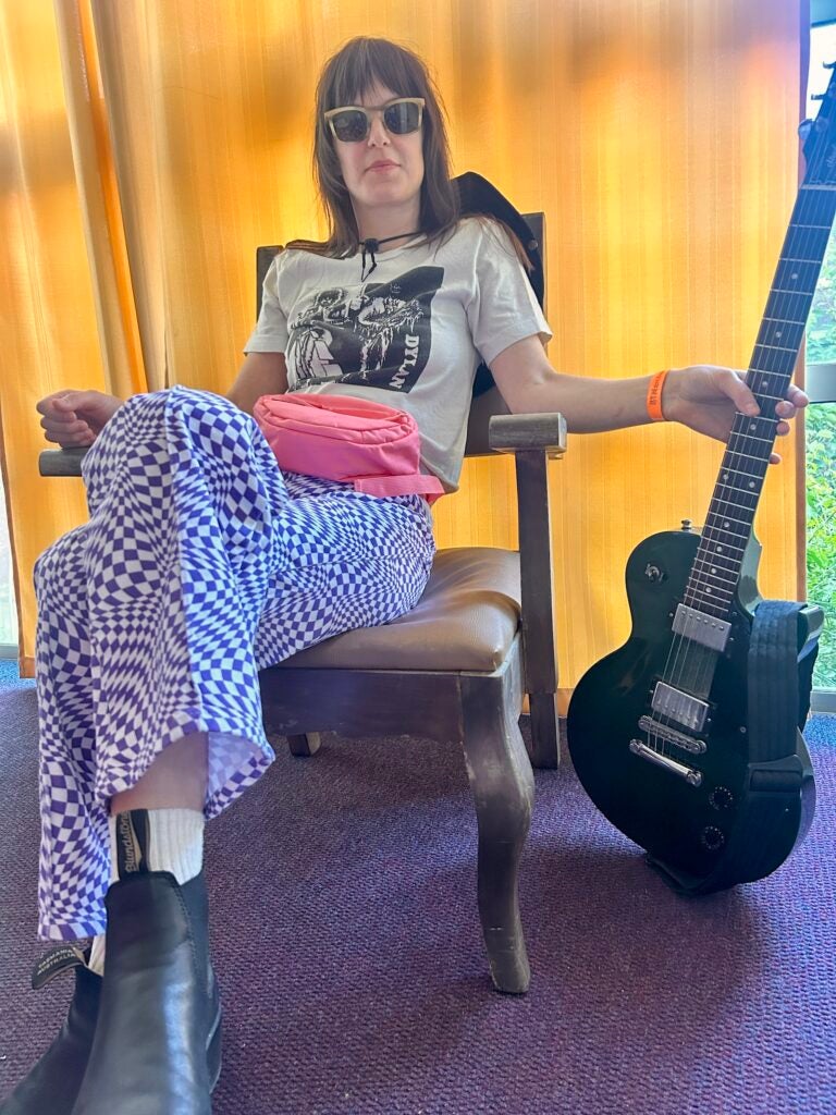 Emily Robb sitting relaxed in a chair with her guitar next to her