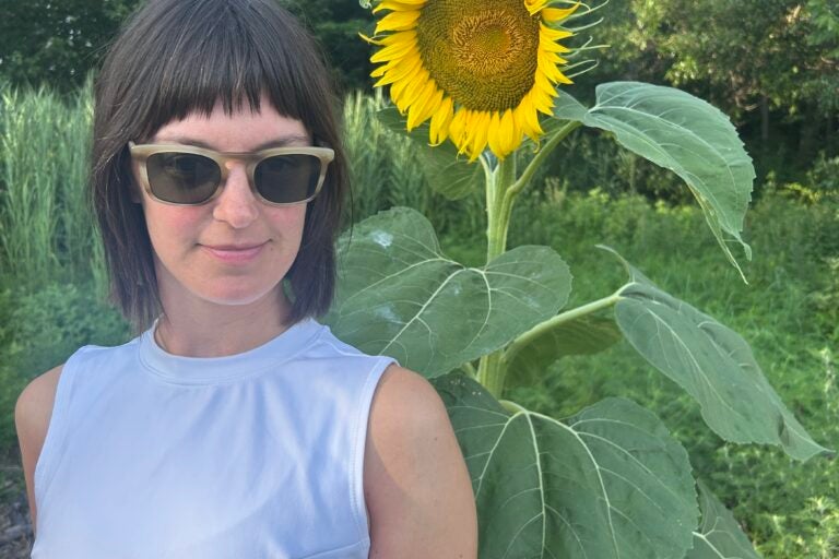 Emily Robb posing for a photo outdoors in front of a sunflower