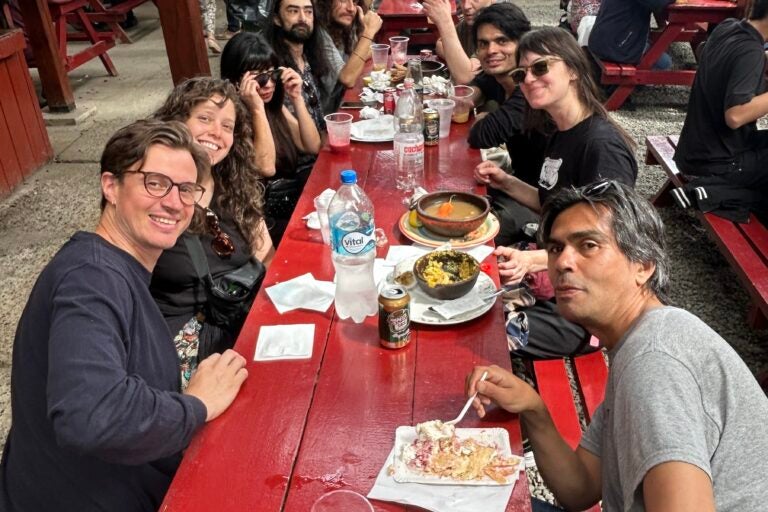 Emily Robb sitting at a long picnic table with many people at an outdoor eating area