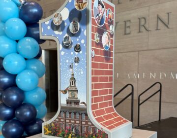 A large sculpture of the numeral 1, decorated with various Philly artifacts