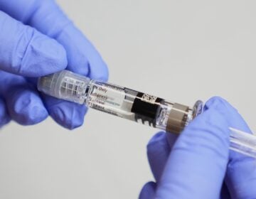 Flu-What to Know A certified medical assistant holds a syringe for a flu vaccine