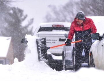Nikos Kesidis uses a snow shovel to clear his driveway in Hockessin, Del., on Sunday, Jan. 25, 2026, as a snow storm moves through the region