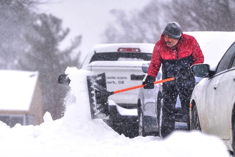 Nikos Kesidis uses a snow shovel to clear his driveway in Hockessin, Del., on Sunday, Jan. 25, 2026, as a snow storm moves through the region