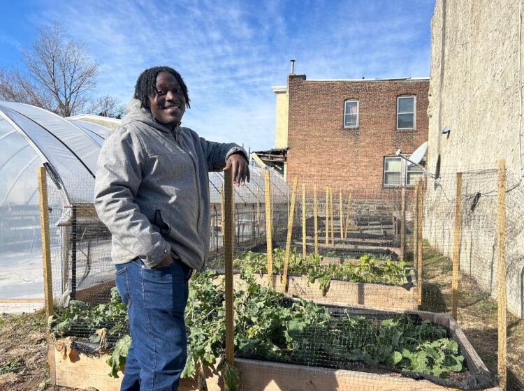 Jovian Patterson standing next to a raised bed filled with greens