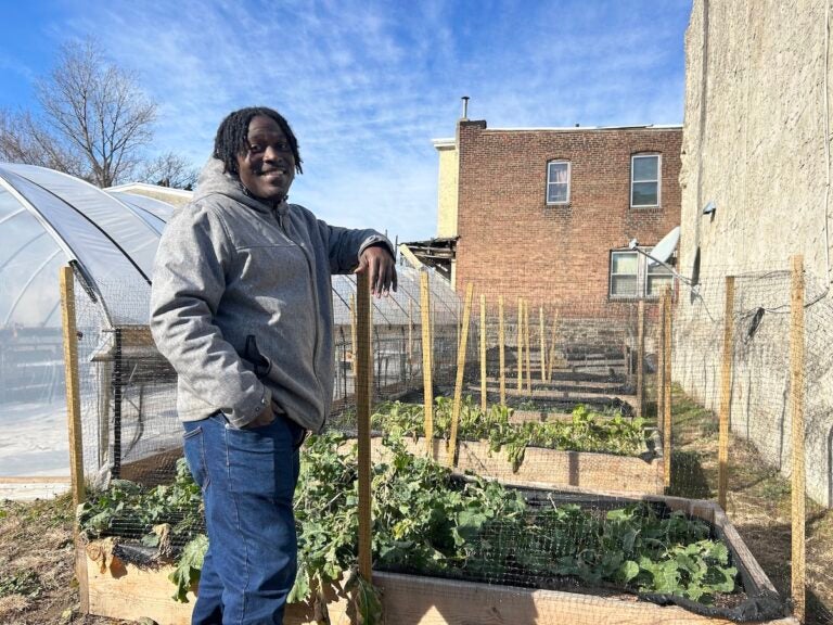Jovian Patterson standing next to a raised bed filled with greens