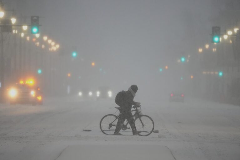 A person pushes a bicycle during a winter storm in Philadelphia, Sunday, Jan. 25, 2026.