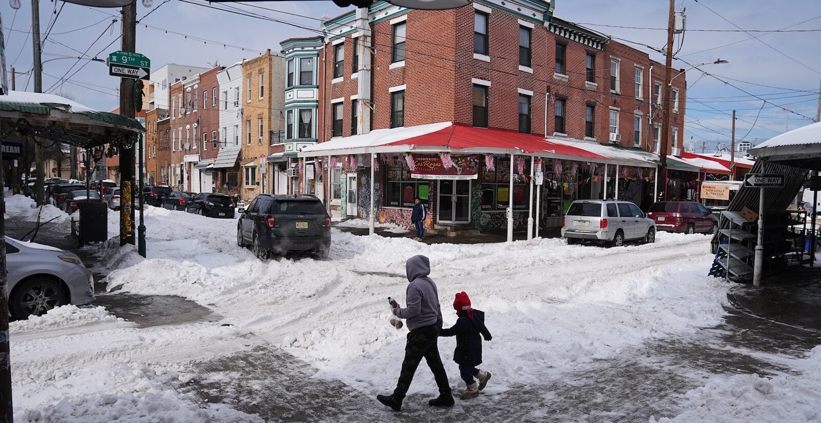 People cross a snow covered street in the aftermath of a winter storm in Philadelphia, Monday, Jan. 26, 2026.