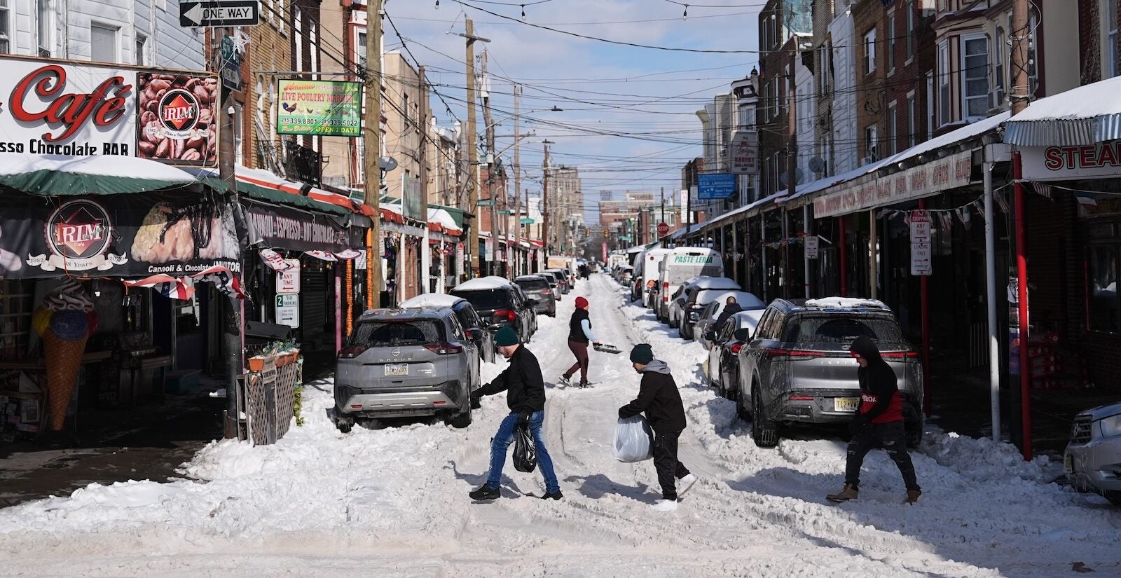 People walk across a snow covered street in the aftermath of a winter storm in Philadelphia, Monday, Jan. 26, 2026.
