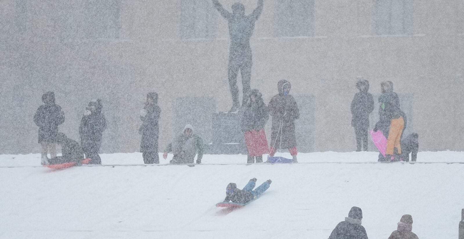 People sled on Philadelphia Art Museum steps by the Rocky statue during a winter storm in Philadelphia, Sunday, Jan. 25, 2026.
