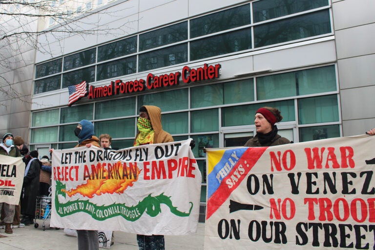 People hold signs protesting the U.S. military intervention in Venezuela