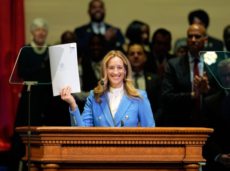 New Jersey Gov. Mikie Sherrill holds up a just signed executive order