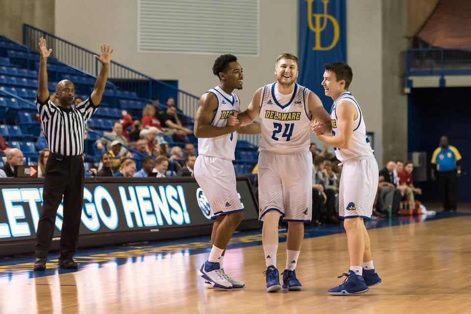 Sean Locke stands in between two teammates on the basketball court