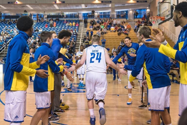 Sean Locke receives high fives from teammates before a basketball game