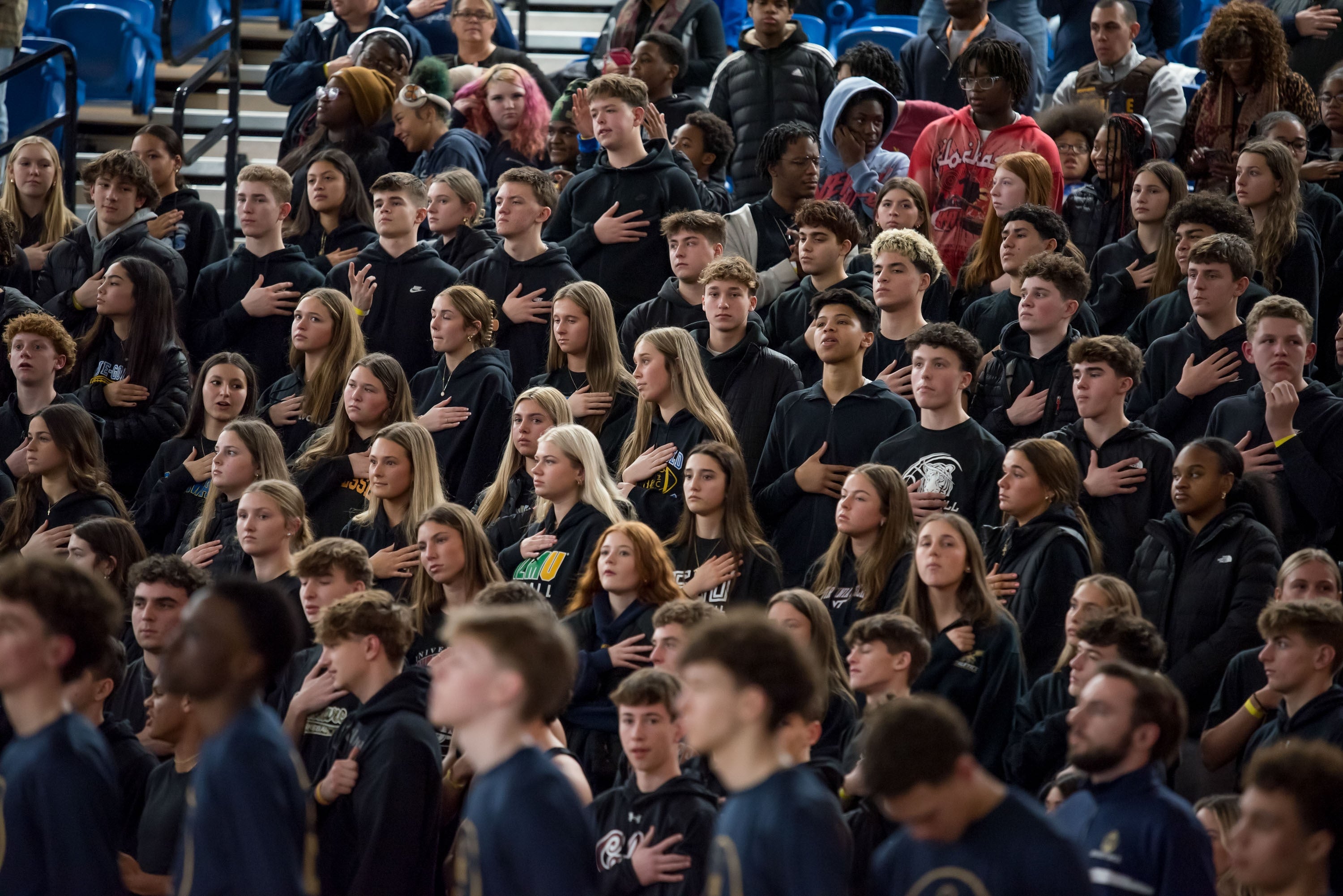 Students and student-athletes with hands over their hearts fill the bleachers during last year’s SL24 Basketball Classic
