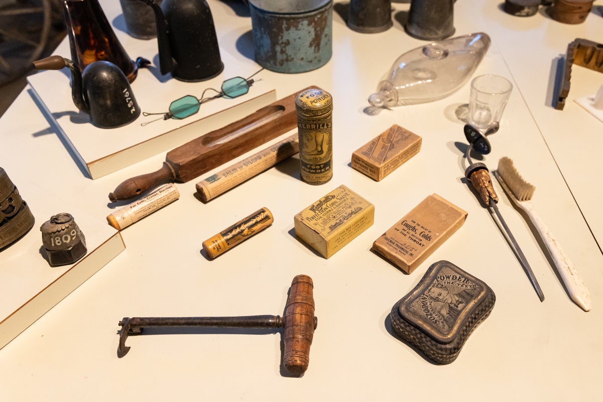 A tooth key, spectacles, hearing aids, common ailment treatments and other medical items on a table