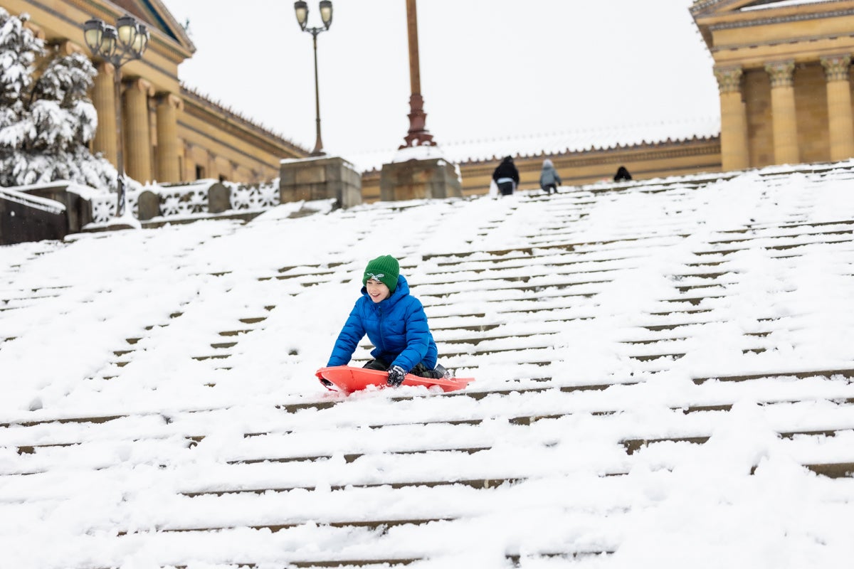 Christian Coretese, 11, rides a sled down the art museum steps after a snowstorm in Philadelphia on February 23, 2026.