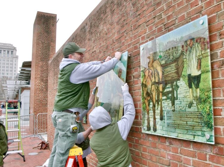 2025 02 19-e lee-philadelphia independence mall presidents house-slavery exhibit restored raising panel National Park Service employees restore the exhibit on slavery to the President's House Site on Independence Mall