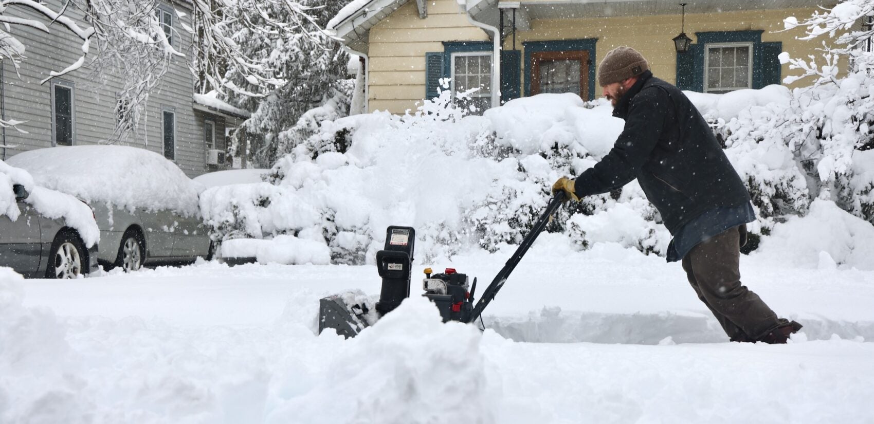 Jeff Motta is using a snowblower to clear the sidewalk in front of a house after a massive snowstorm in Moorestown, New Jersey