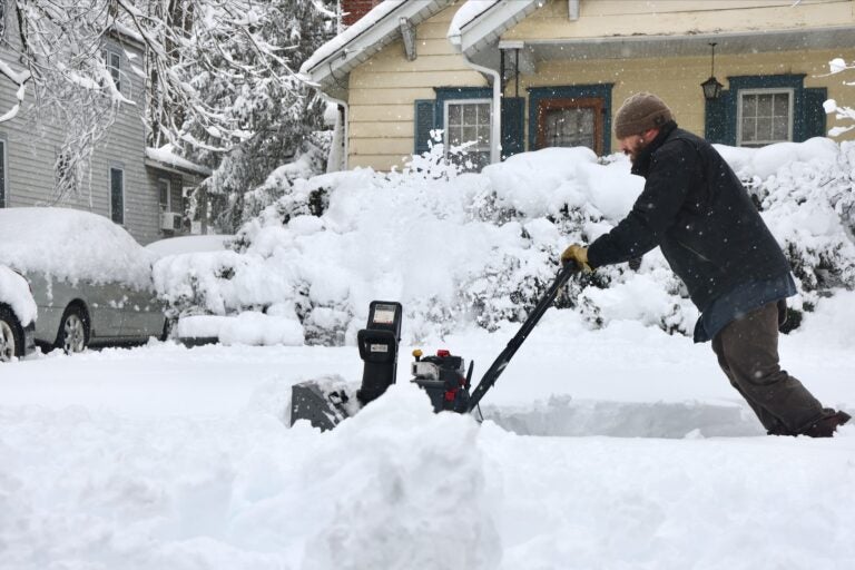 Jeff Motta is using a snowblower to clear the sidewalk in front of a house after a massive snowstorm in Moorestown, New Jersey