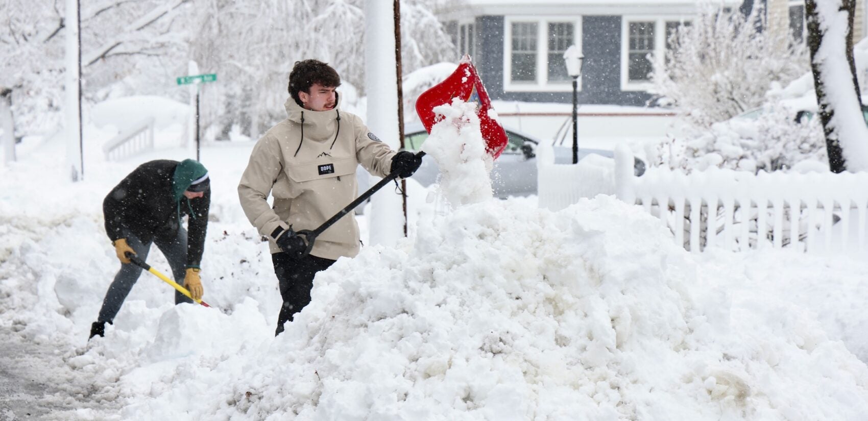 Two people shoveling out driveways and sidewalks on a residential street in Moorestown after a huge snowstorm in Moorestown, New Jersey