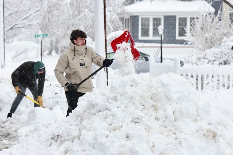 Two people shoveling out driveways and sidewalks on a residential street in Moorestown after a huge snowstorm in Moorestown, New Jersey