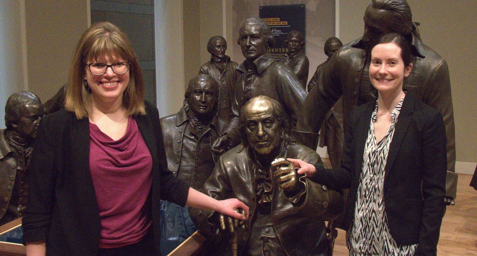Sarah Winski and Elena Popchoc pose with bronze statues