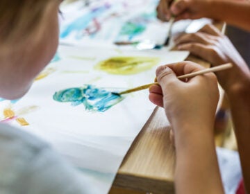 Close up of elementary student using watercolors for painting on art class in the classroom.