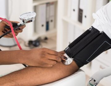 A physician measures a patient's blood pressure with a stethoscope.