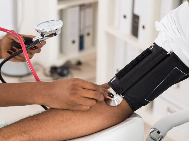 A physician measures a patient's blood pressure with a stethoscope.