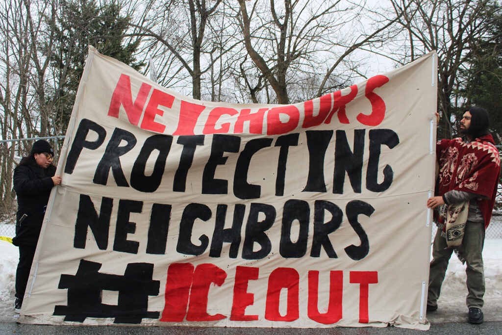 a sign reads NEIGHBORS PROTECTING NEIGHBORS #ICEOUT