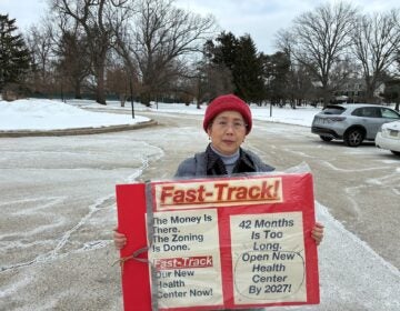 Mingchu Pearl Huynh holds a sign about fast-tracking opening a new health center
