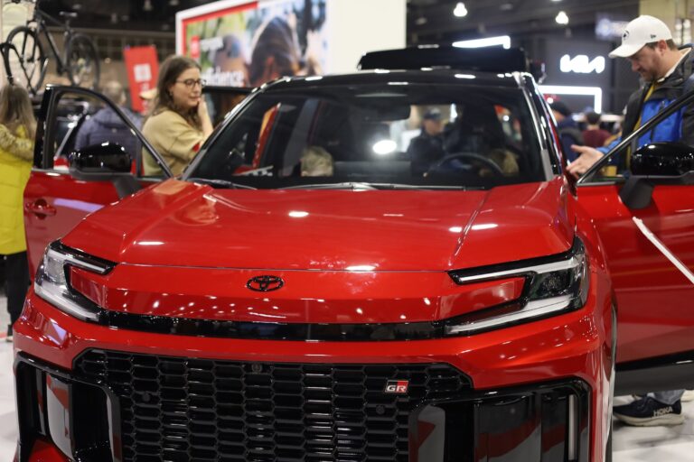 People inspecting a new hybrid car at the auto show