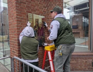 Workers restore panels to the slavery exhibits at the President's House Site
