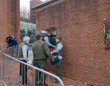 Workers restore panels to the slavery exhibits at the President's House Site on Independence Mall