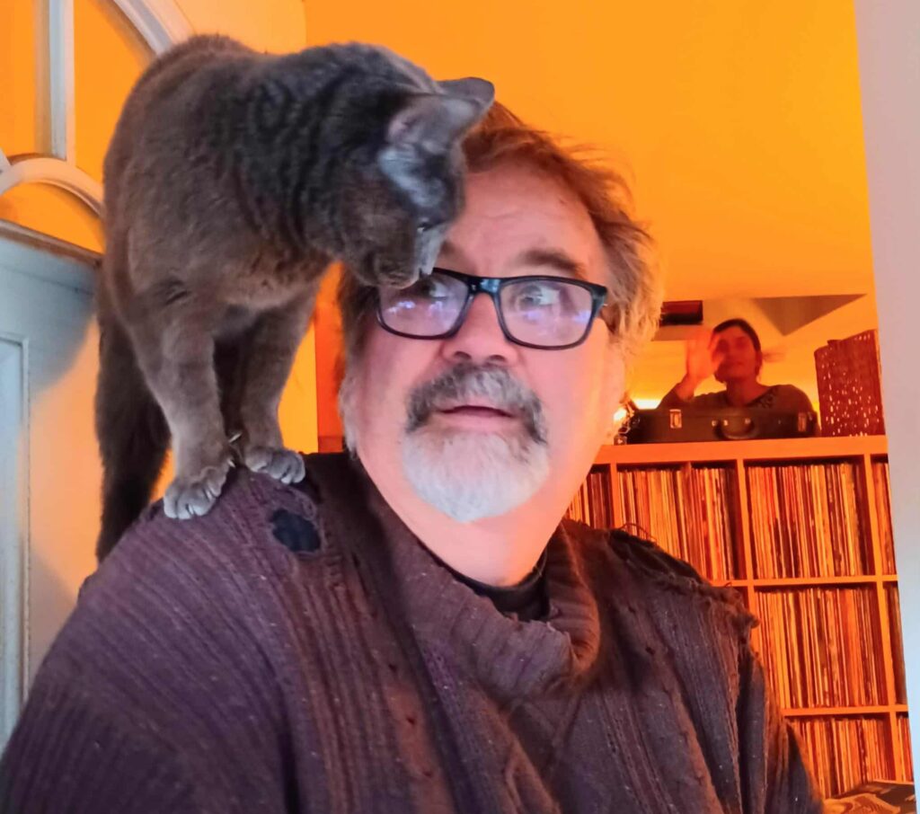 Steven Tobin at home with his cat on his shoulder