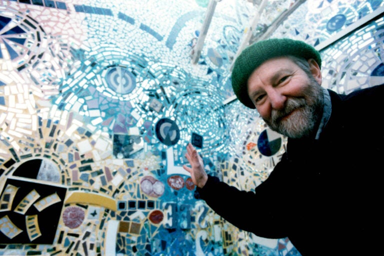 Isaiah Zagar waving to the camera in the courtyard at the magic gardens