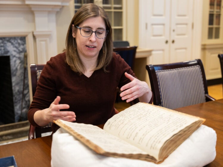 Adrianna Link, curator of the History of Science Library and Museum at American Philosophical Society, carefully handles the society’s minute book from the 1790s in a library designed to resemble Benjamin Franklin’s.