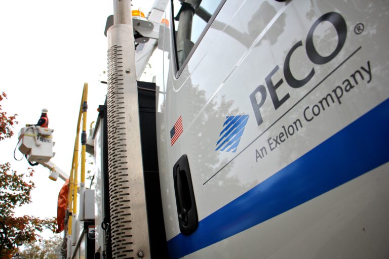A PECO truck has the logo on the side, as a worker is using a lift to reach something high.